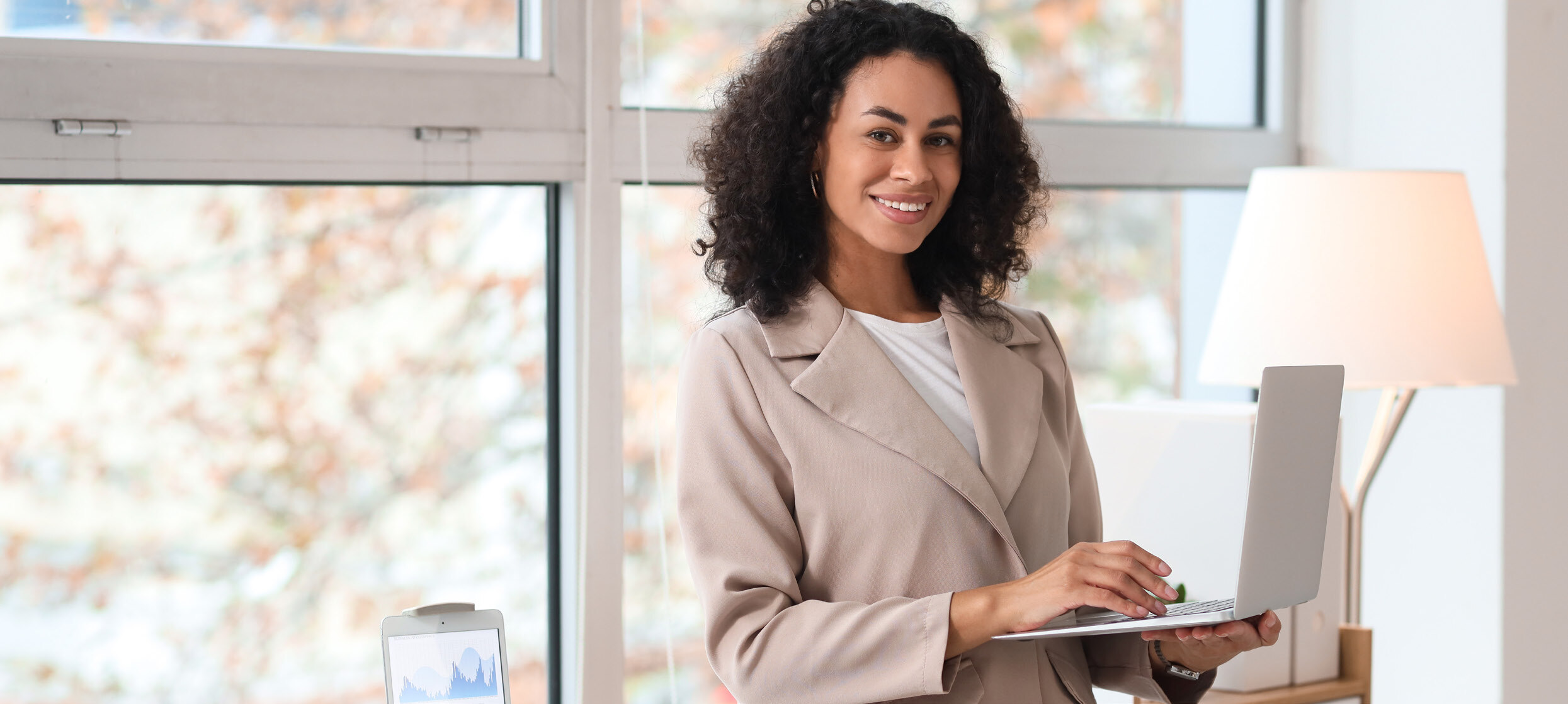 A banking professional working on a laptop by a sunlit window