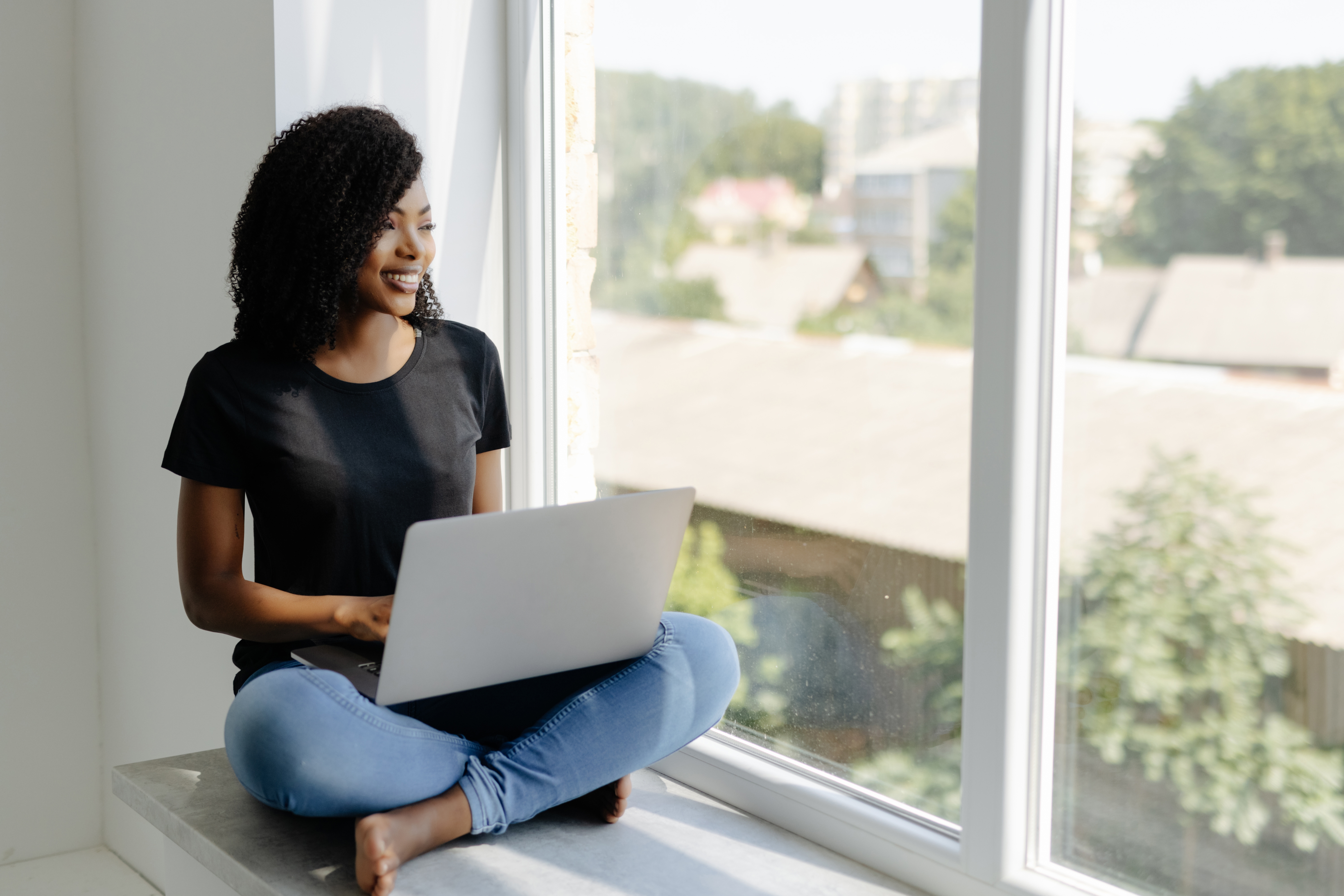 Client working on a laptop by a sunlit window