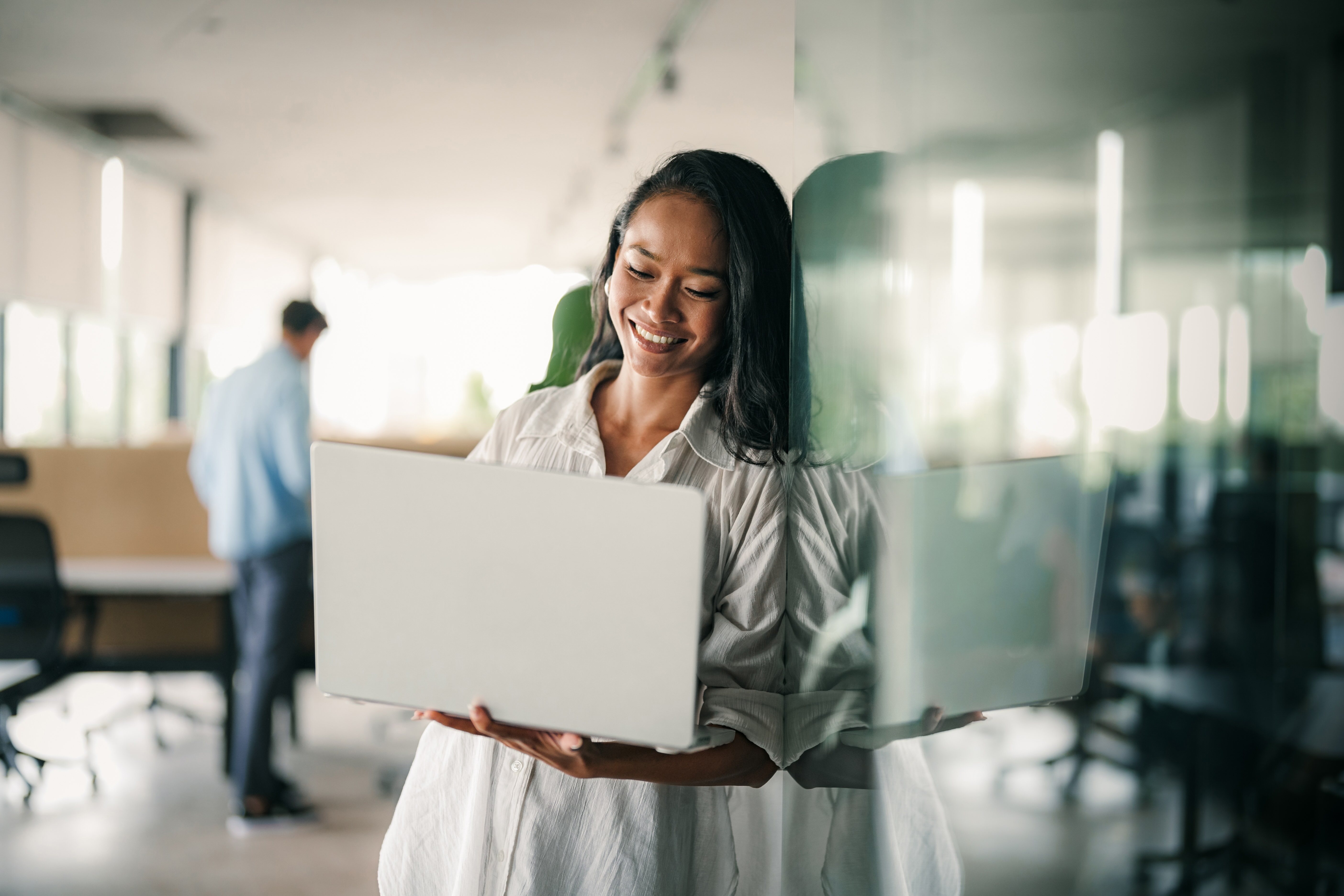 Professional smiling while working on a laptop in a bright office